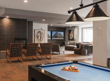 A pool table with a blue cloth and a pool game set up in a room with a fireplace and a couch.